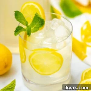 Glass of mint lemonade garnished with sliced lemon and fresh mint.