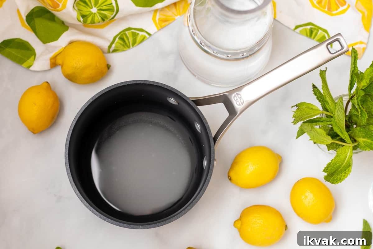 Sugar and water heating in a saucepan next to lemons and mint.