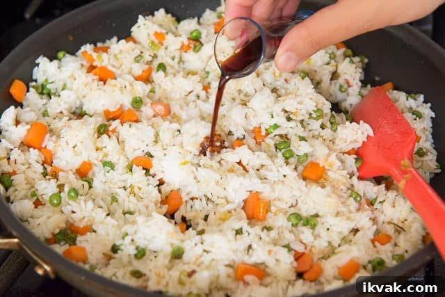 Pouring Soy Sauce Over Rice with peas and Carrots