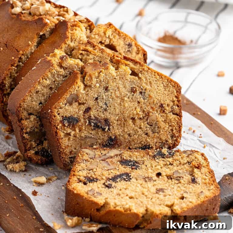 Sliced date walnut loaf on white paper on a wooden board. Striped background.
