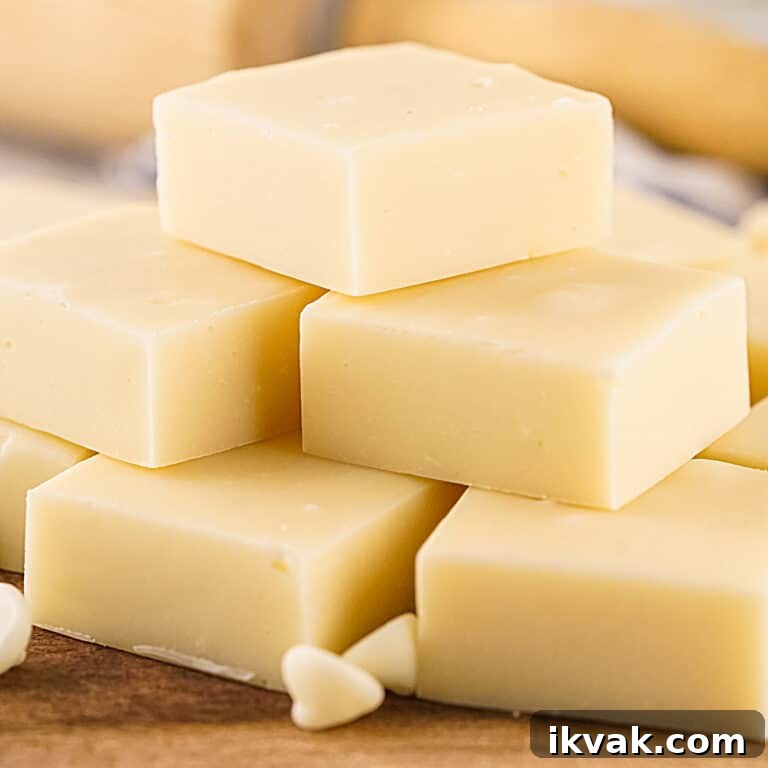 Pile of white chocolate fudge squares on a wooden surface.