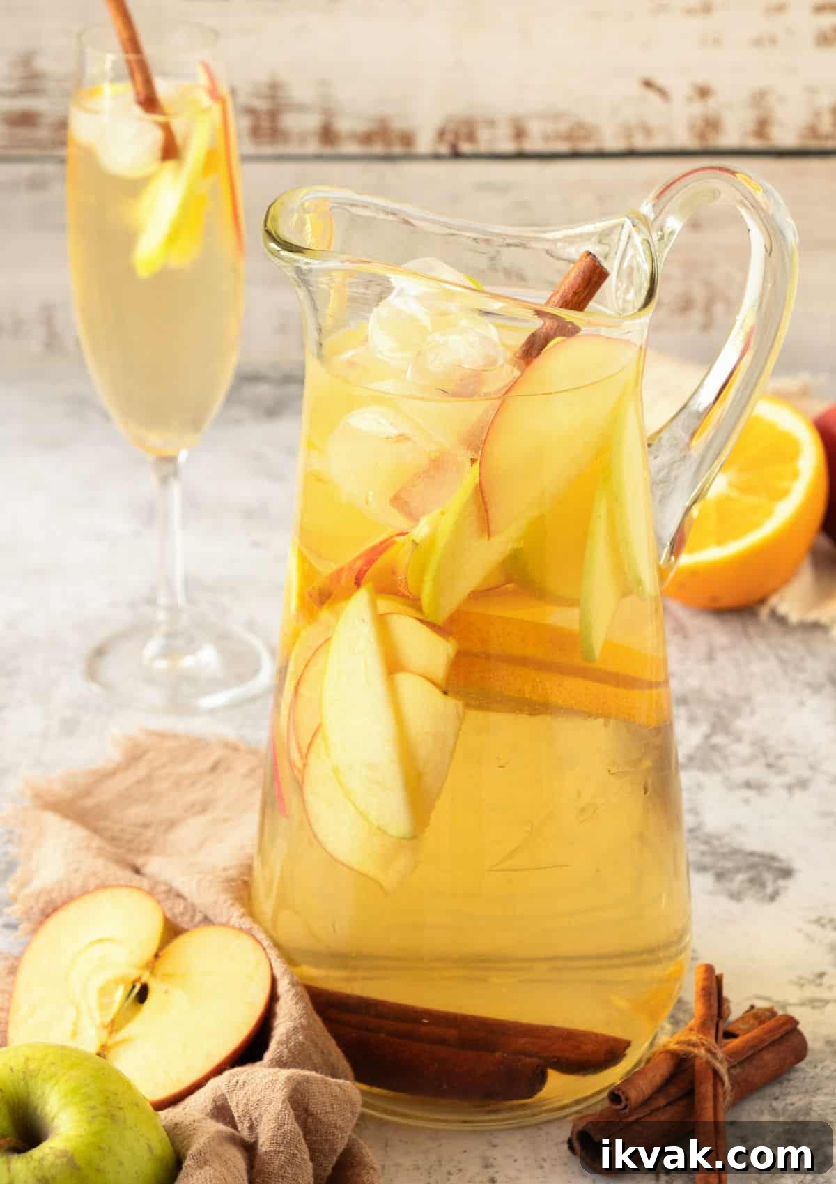 Christmas Potluck Ideas: Crowd-Pleasing Dishes & Menu Tips 3 Pitcher of apple cider with apple and orange slices. Grey background, glasses, fruit.