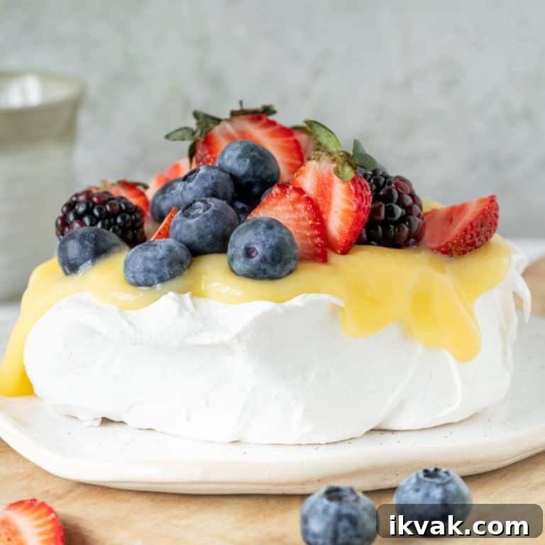 Lemon and berries pavlova on a wooden surface with grey background.