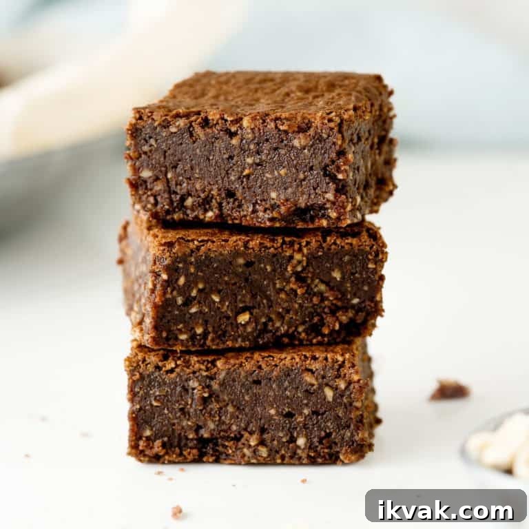 Close up stack of three brownies on a white surface with light blue and cream colored background.