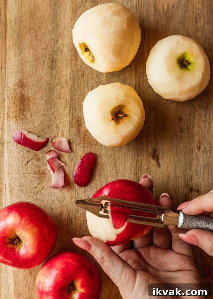 Hands peeling apples on a wood board.