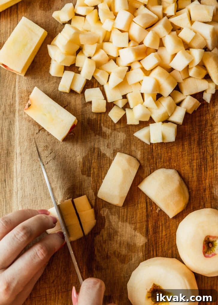 Hands dicing apples on a wood board.
