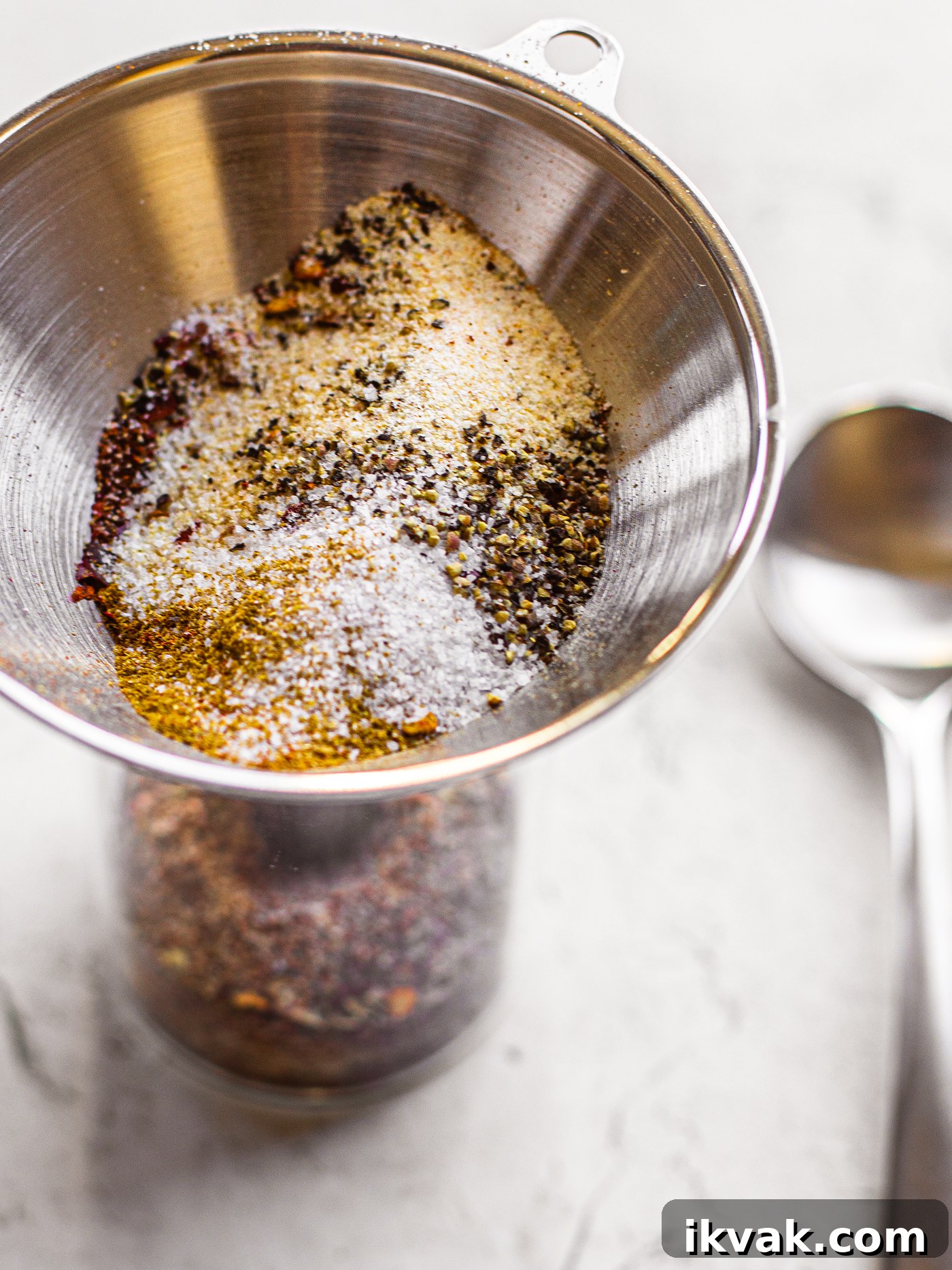 Funnel inserted into a glass jar with a spice blend.