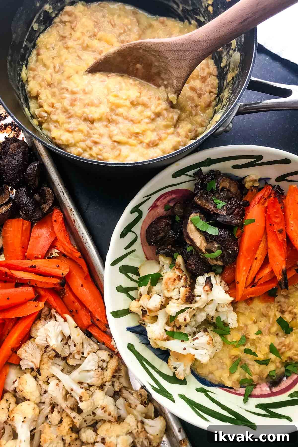 Yellow cooked grains with roasted carrots, cauliflower and mushrooms on top with the pot of faro and lentil and the tray of roasted veggies in the background.