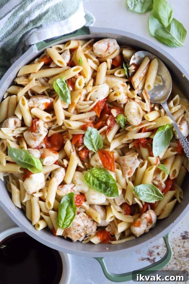 Overhead photo of balsamic chicken pasta in a large skillet, garnished with fresh basil