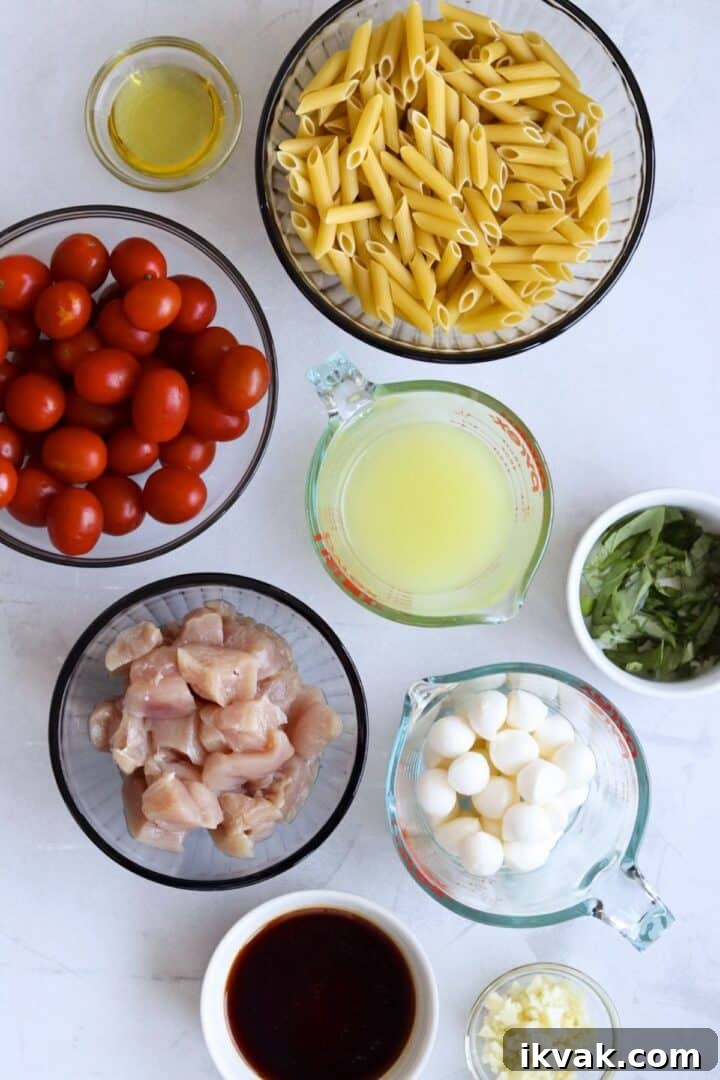 Ingredients for balsamic chicken pasta displayed in small bowls on a white marble counter