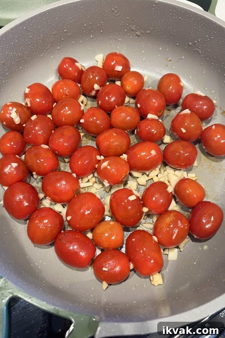 Cherry tomatoes and garlic mixed in a large saucepan