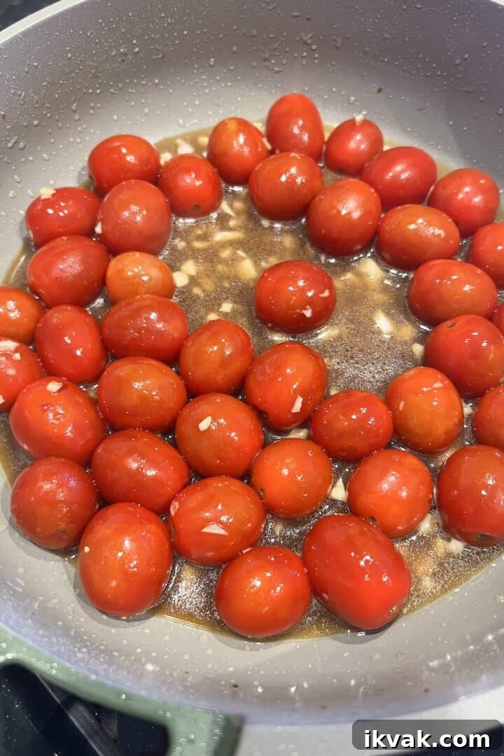 Balsamic vinegar and chicken broth added to cherry tomatoes in a large skillet