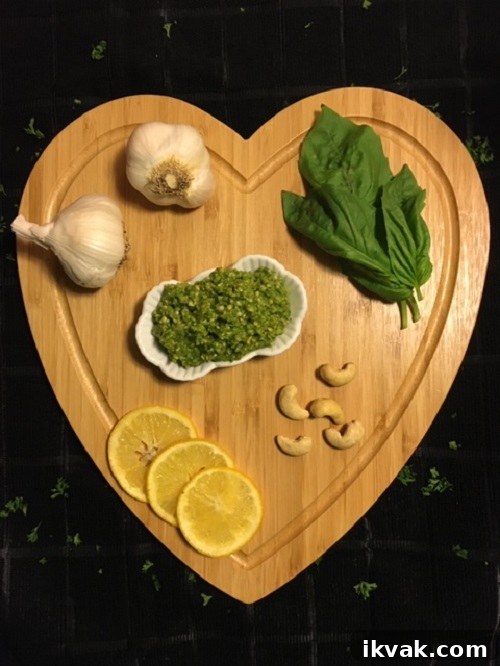 cashew basil pesto on cutting board surrounded by garlic lemon cashews and basil