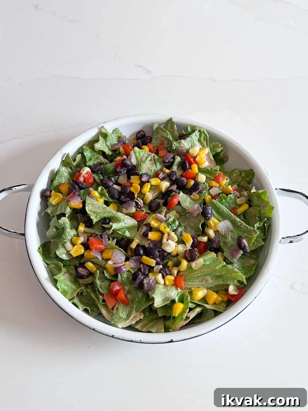 Dressed lettuce in serving dish with corn salsa on top.