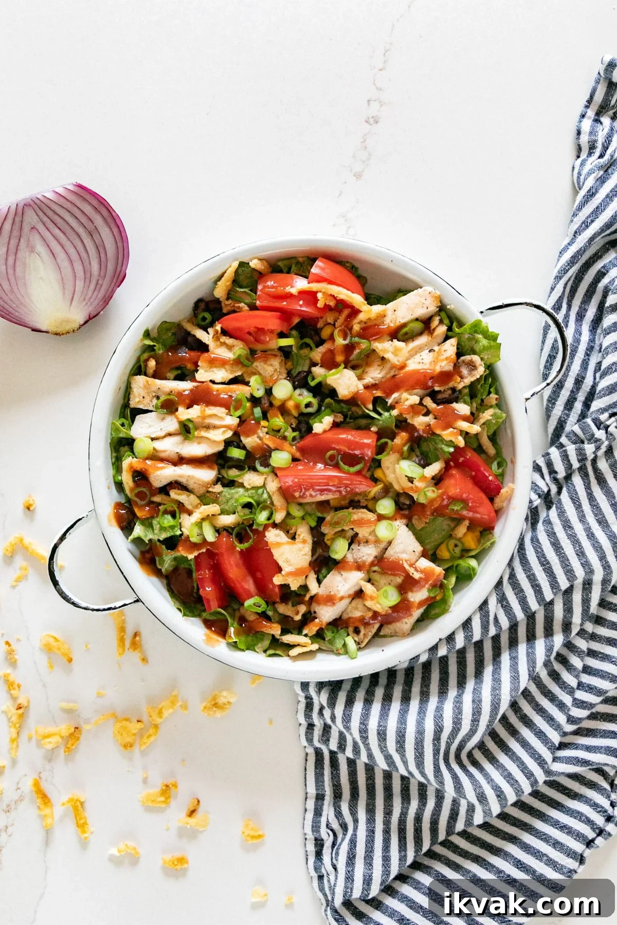 An overhead image of this salad with a half red onion, striped napkin and fried onions around it.