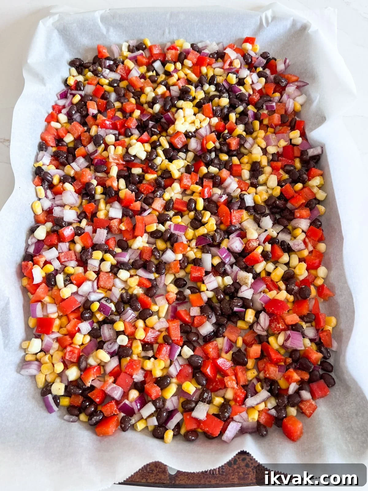 Ingredients for the corn salsa mixed together on a sheet pan lined with parchment.