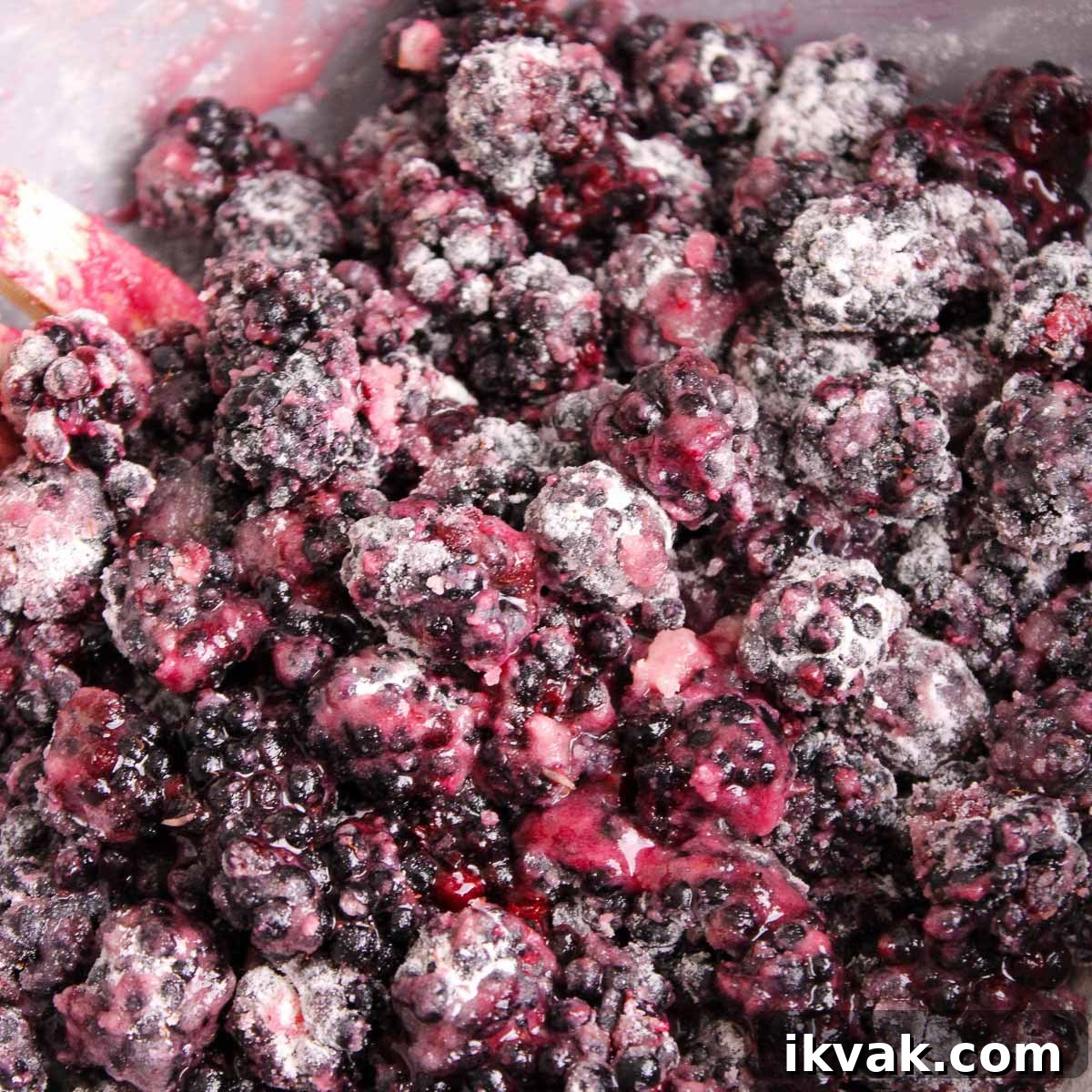 Mixing the fresh blackberries with flour, sugar, and lemon juice in a mixing bowl.