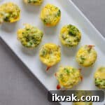 A tray of mini broccoli and cheddar egg bites on a gray table.
