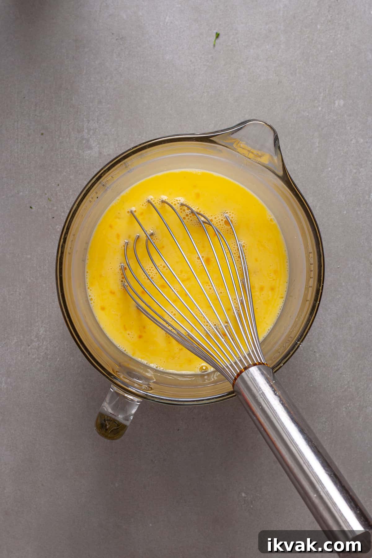 Eggs and milk whisked together in a large measuring cup.