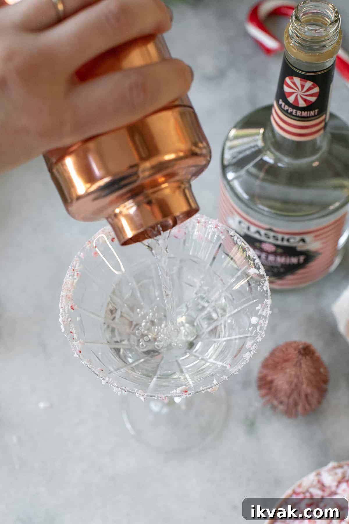 Pouring a peppermint martini into a glass.