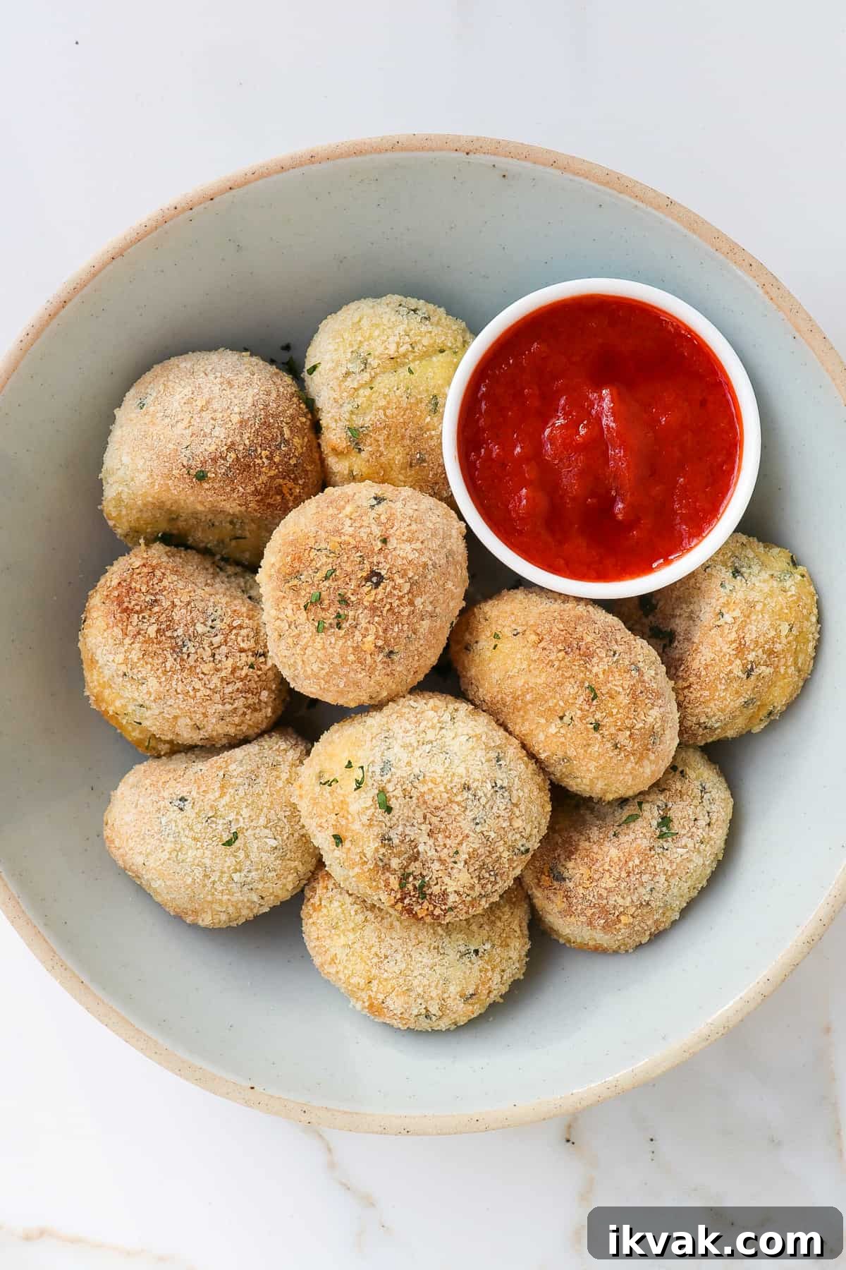 Crispy Air Fryer Potato Croquettes Recipe 2 Potato croquettes in a bowl with marinara sauce.