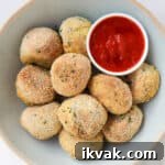 Potato croquettes in a bowl with marinara sauce.