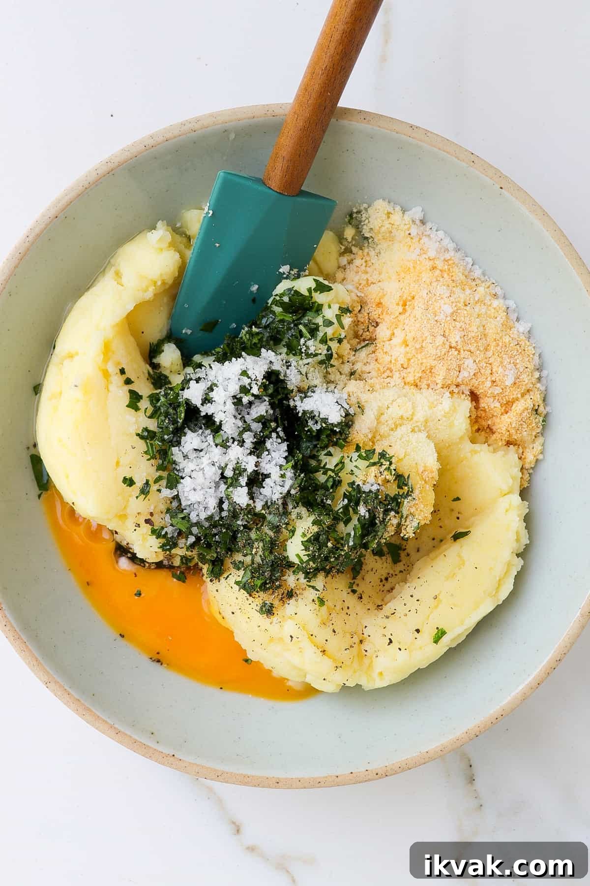 Crispy Air Fryer Potato Croquettes Recipe 5 Mashed potatoes, egg, herbs and seasoning in a bowl with a spatula.