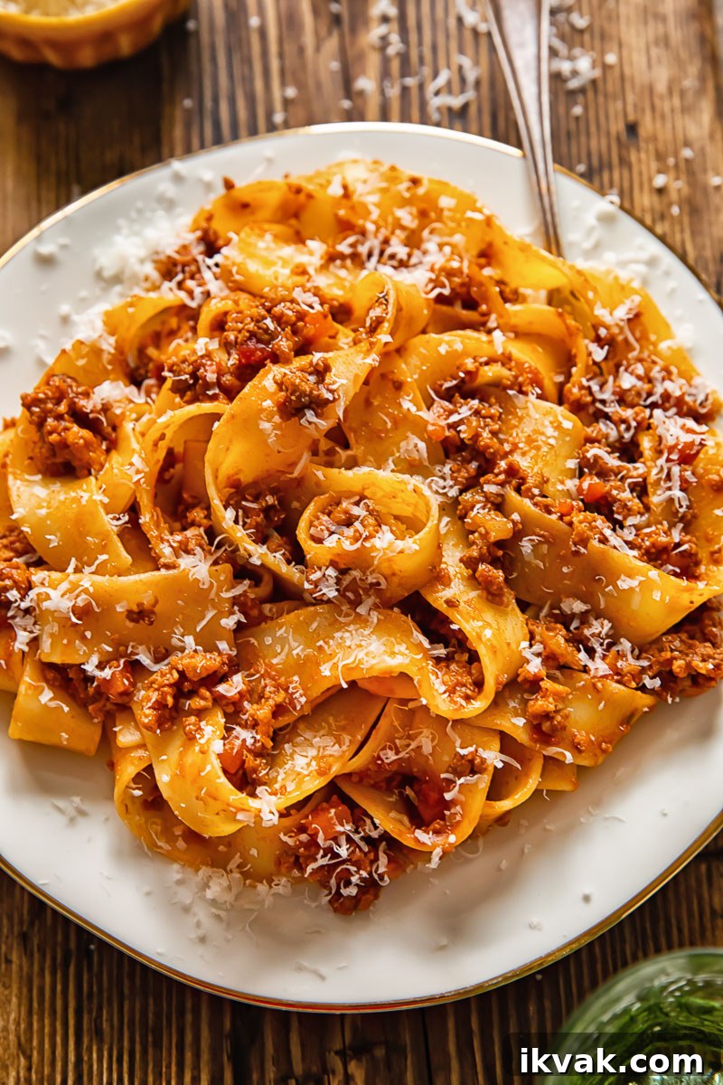 pasta with ragu sauce on a white plate and a fork