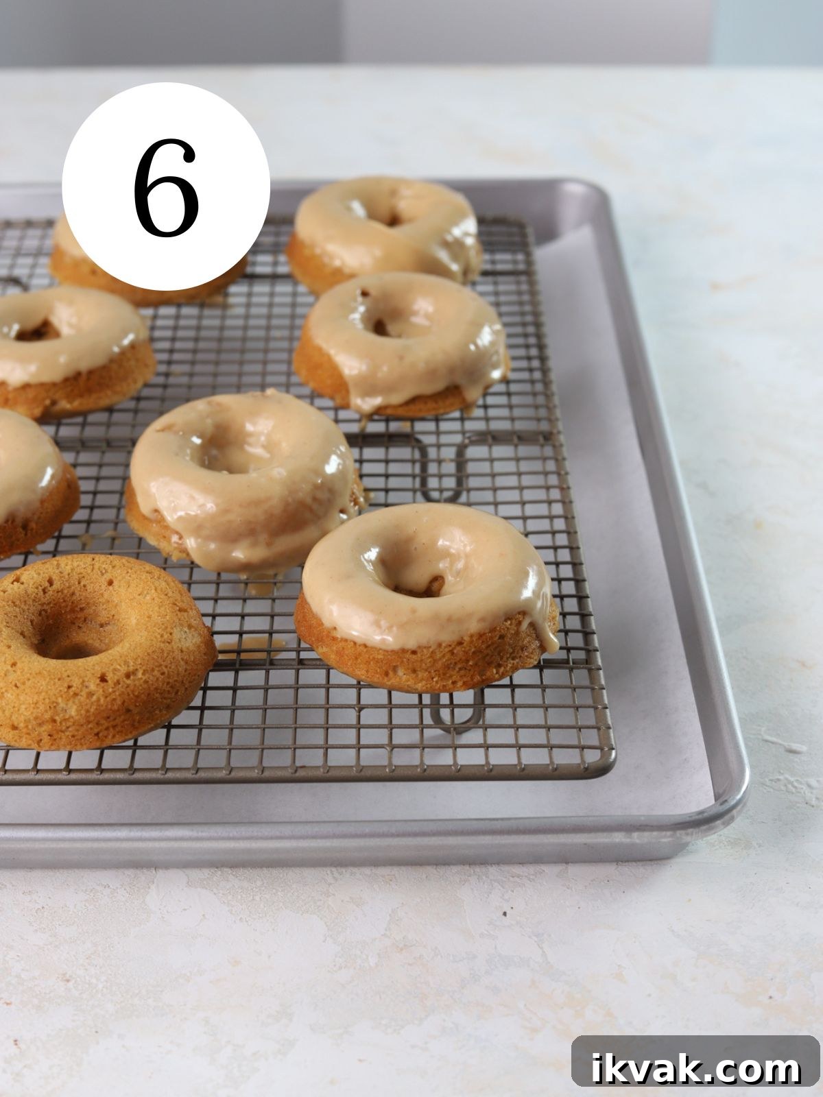 Irresistible Peanut Butter Donuts Recipe — Soft, Gooey, Homemade 9 Donuts with peanut butter glaze on top on a wire rack set on a baking sheet.