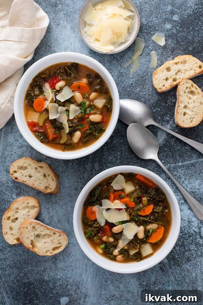 Two bowls of bean and vegetable soup and crusty bread next to them