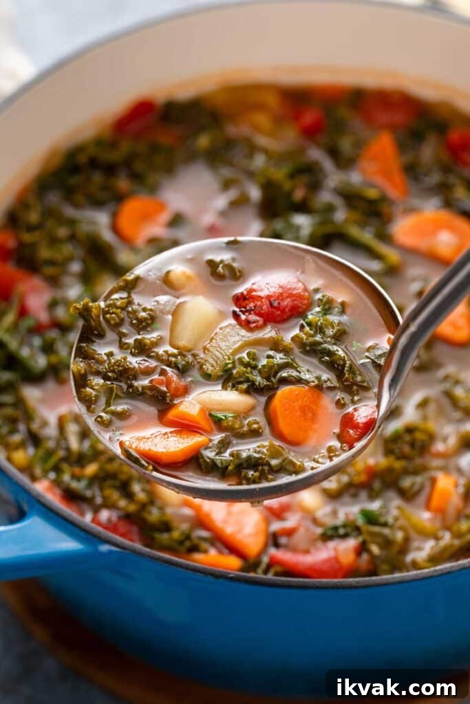 Ladle of white bean and hearty greens soup lifted from a pot.