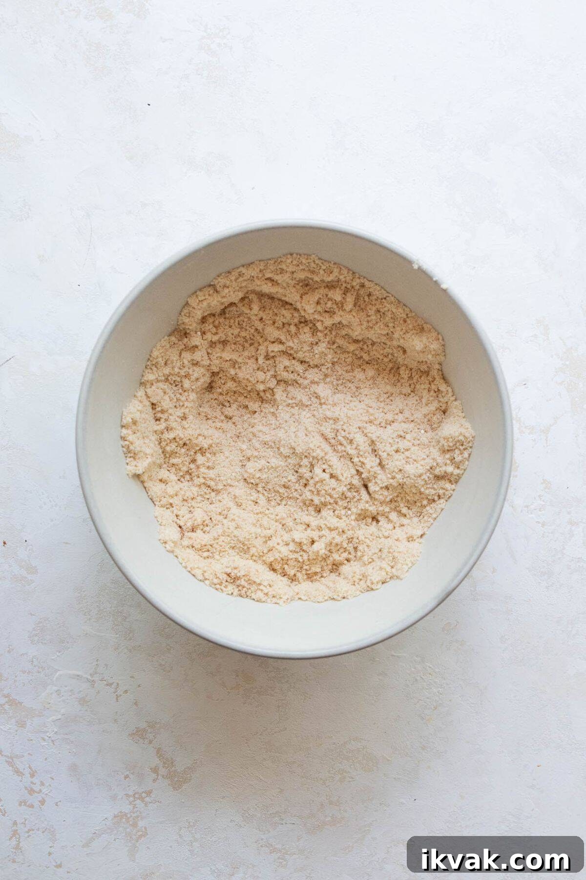 High-Protein Banana Muffins for Breakfast and Snacks 4 Dry ingredients for banana protein muffins whisked together in a bowl, including almond flour and vanilla protein powder.