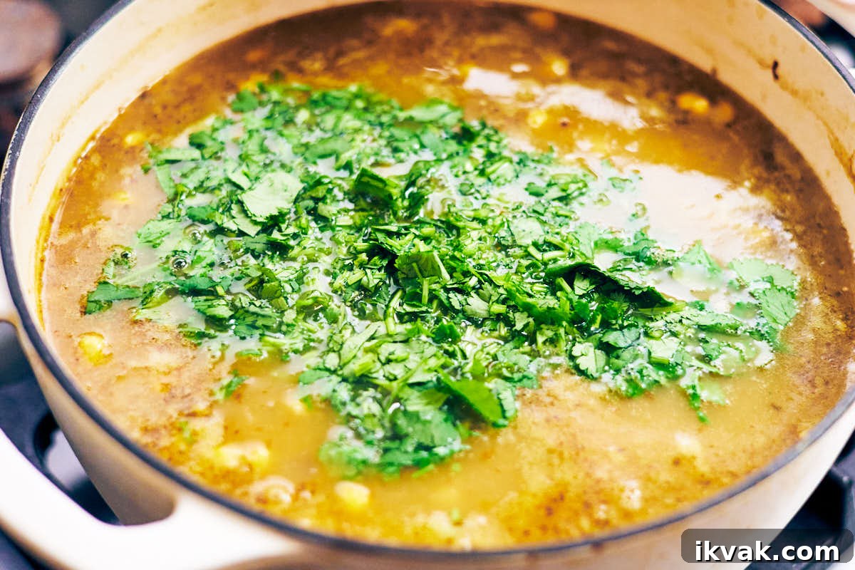 Chopped cilantro added on top of a pot of green chili soup.