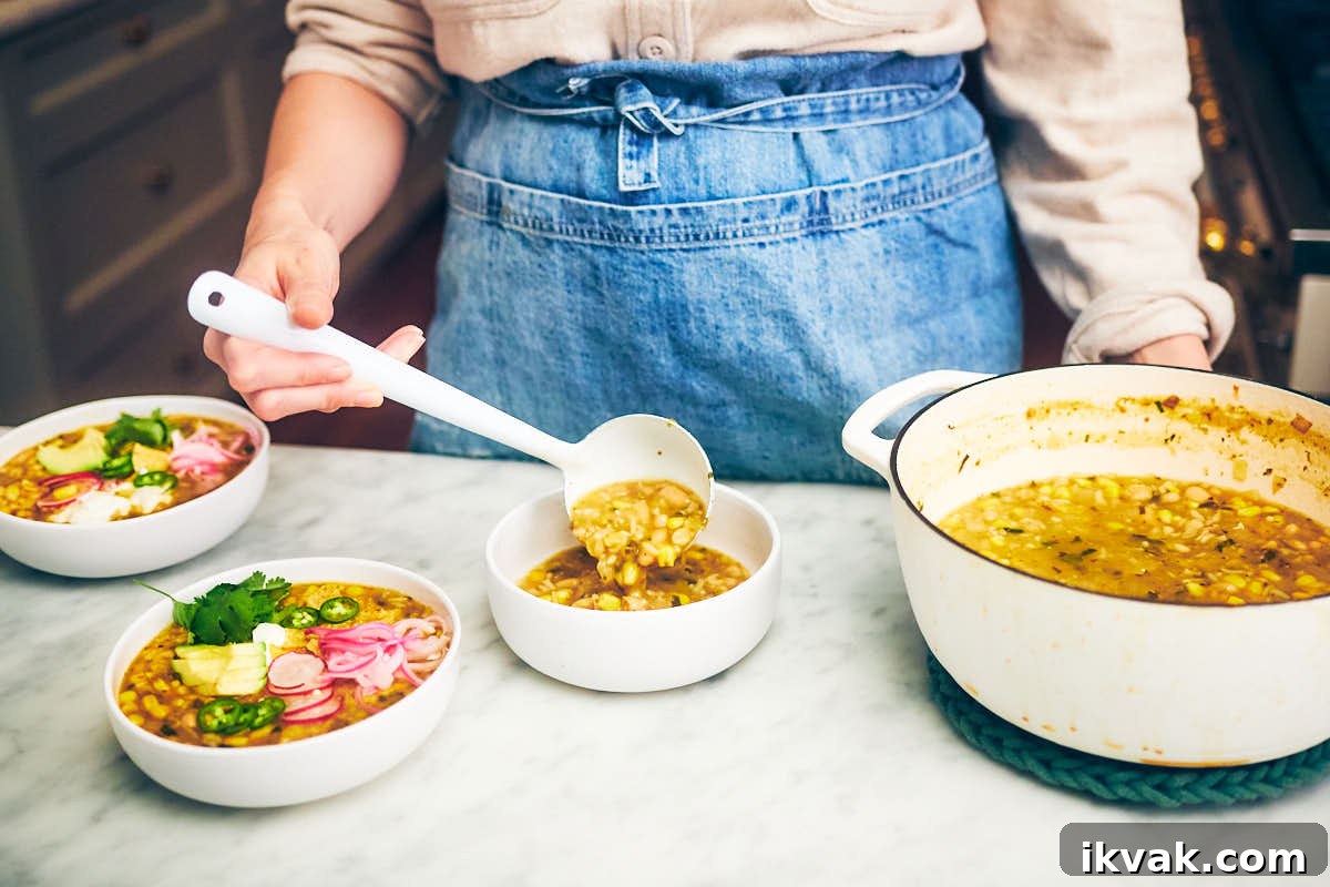 A woman spooning green chili, corn and rice soup into bowls on a kitchen counter.
