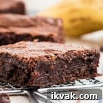 a close up of a moist banana brownie with a banana in the background