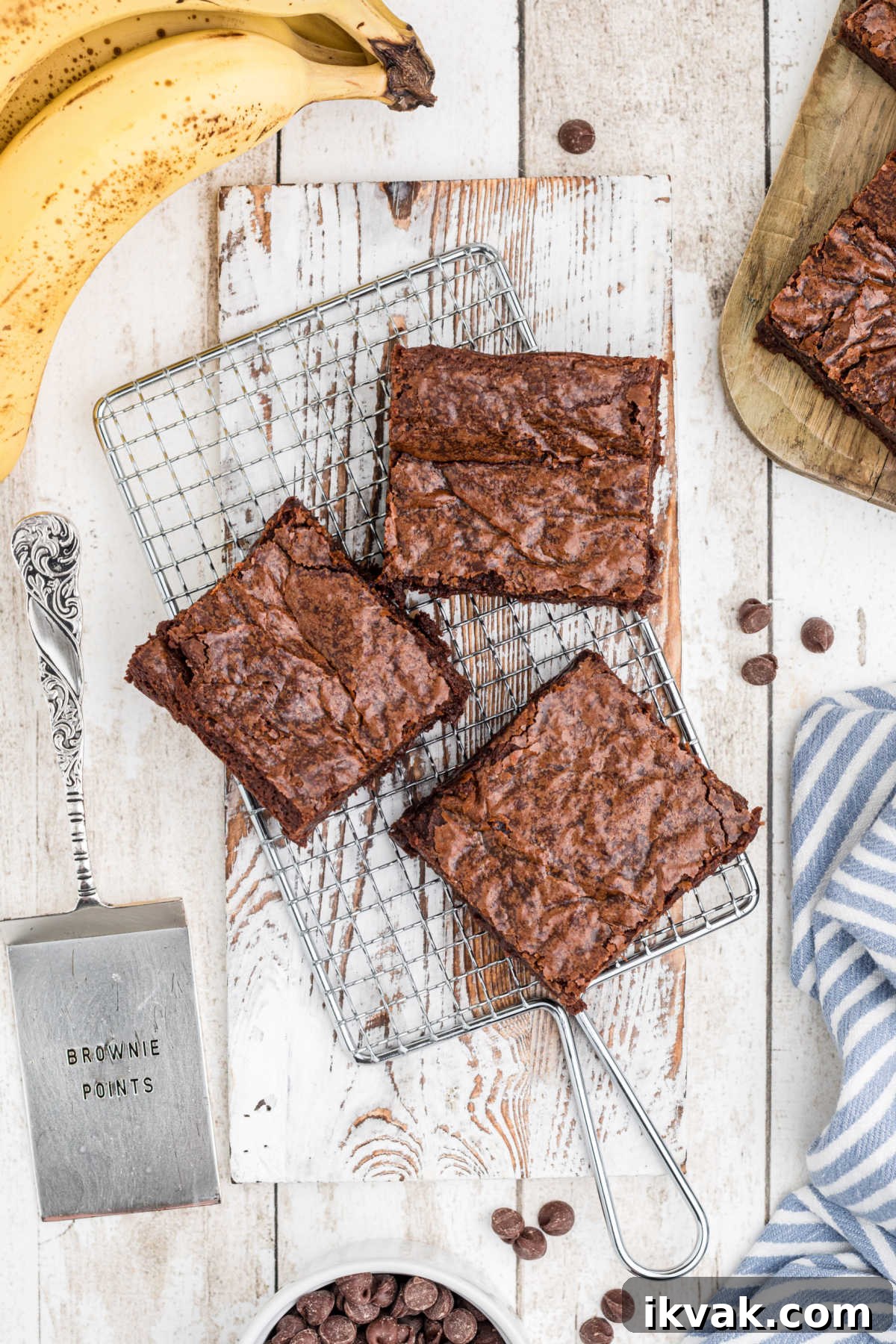 overhead picture of three brownies on a cooling rack with bananas in the background