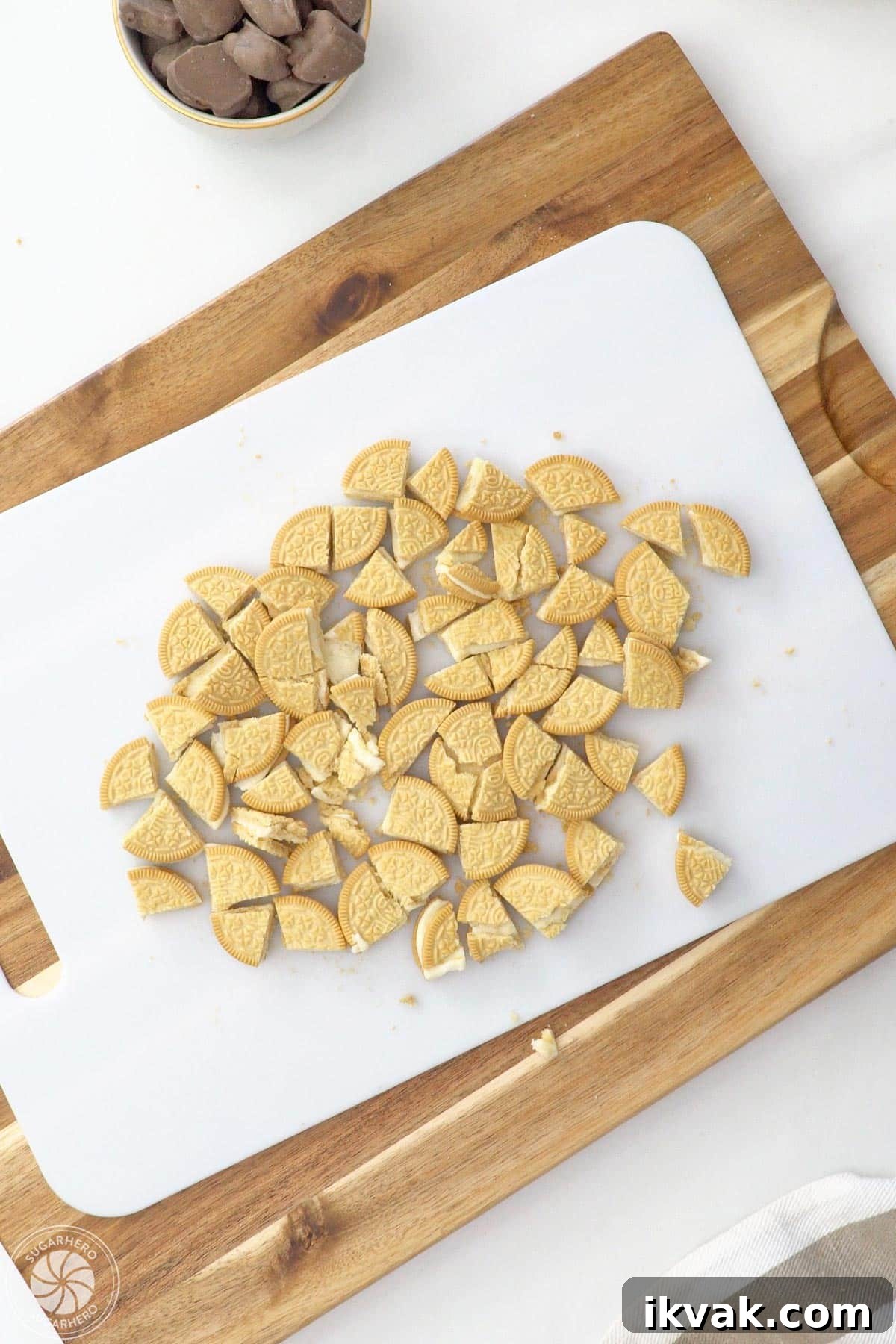 Chopped vanilla sandwich cookies on a white cutting board.