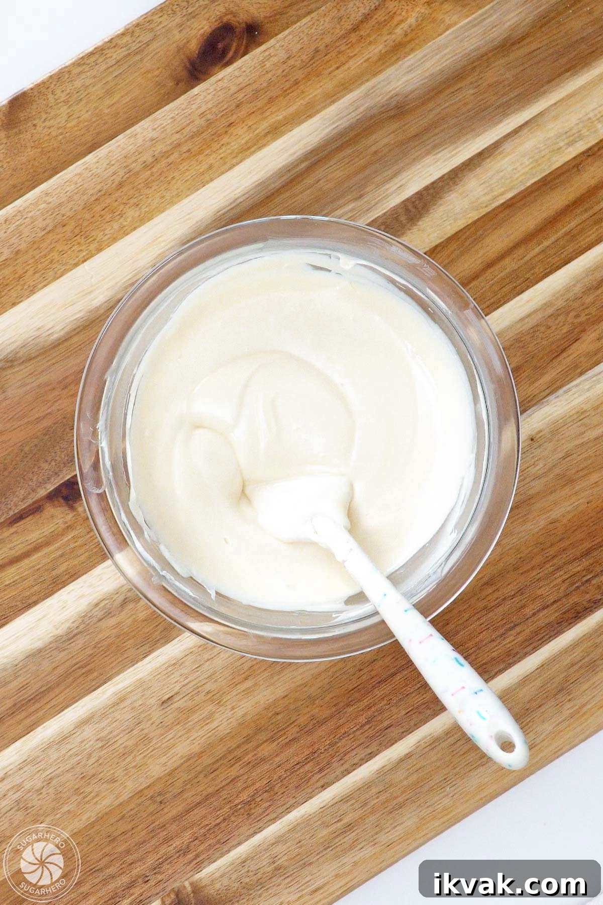 Bowl of melted white candy coating on a wooden cutting board.