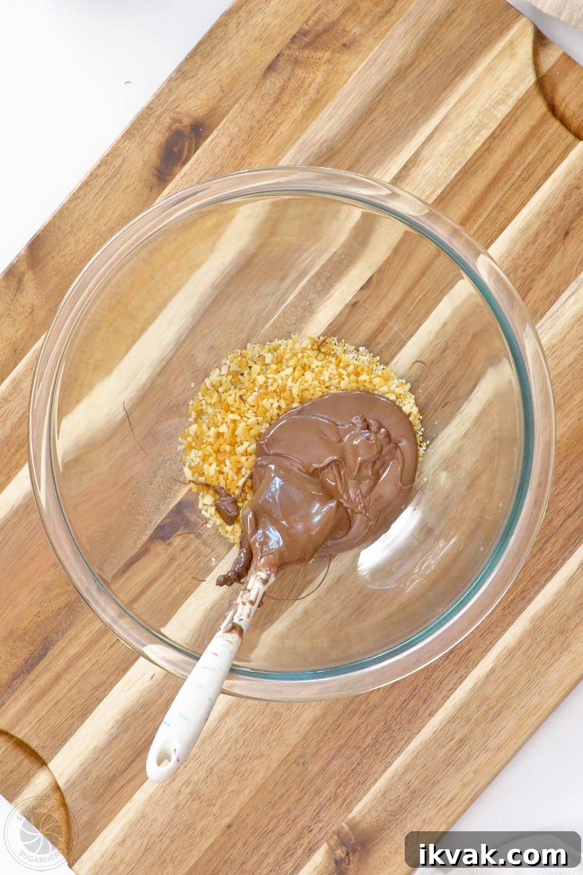 Brown candy coating added to popping candy in a large glass bowl.