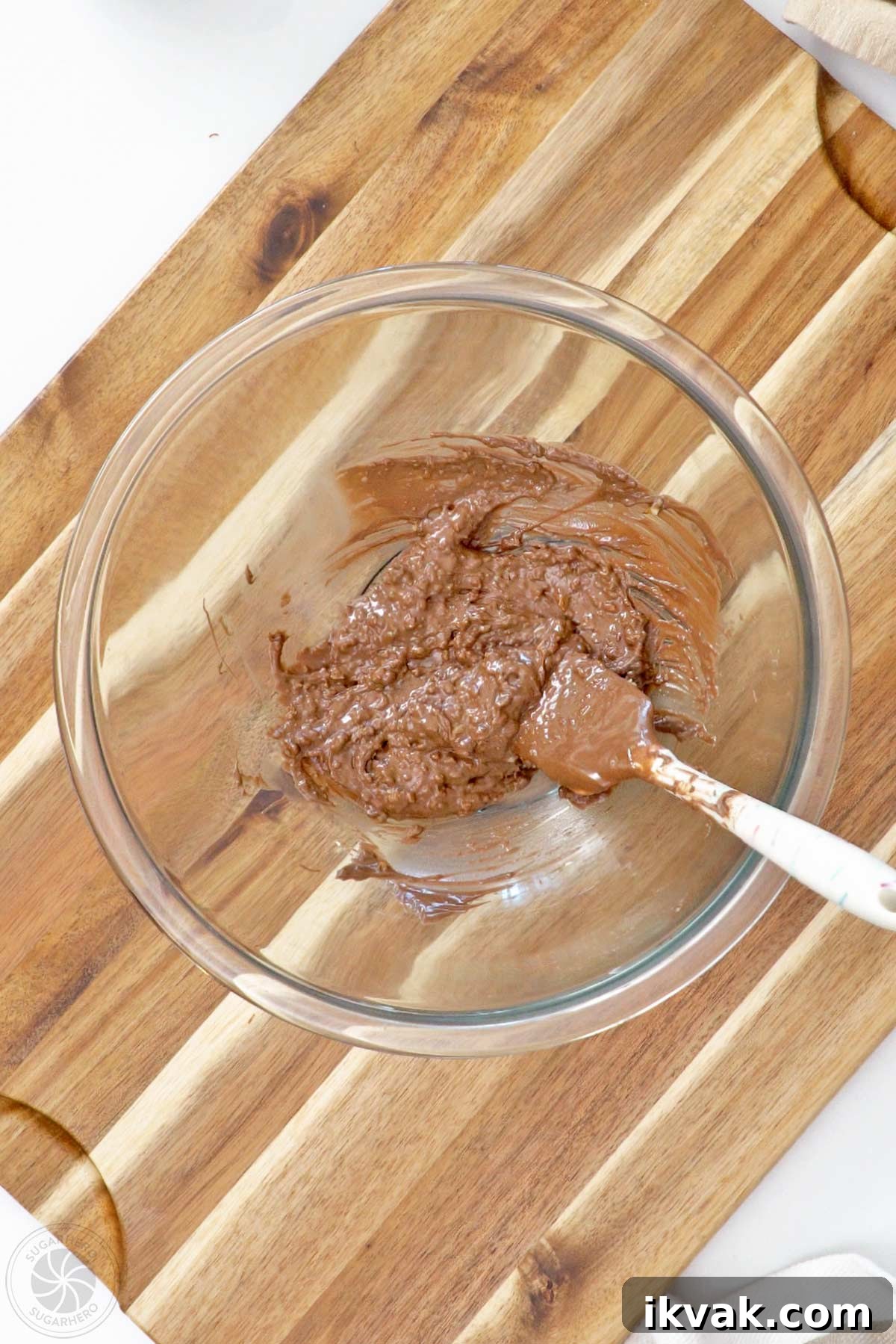 Popping candy and melted candy coating stirred together in a glass bowl.