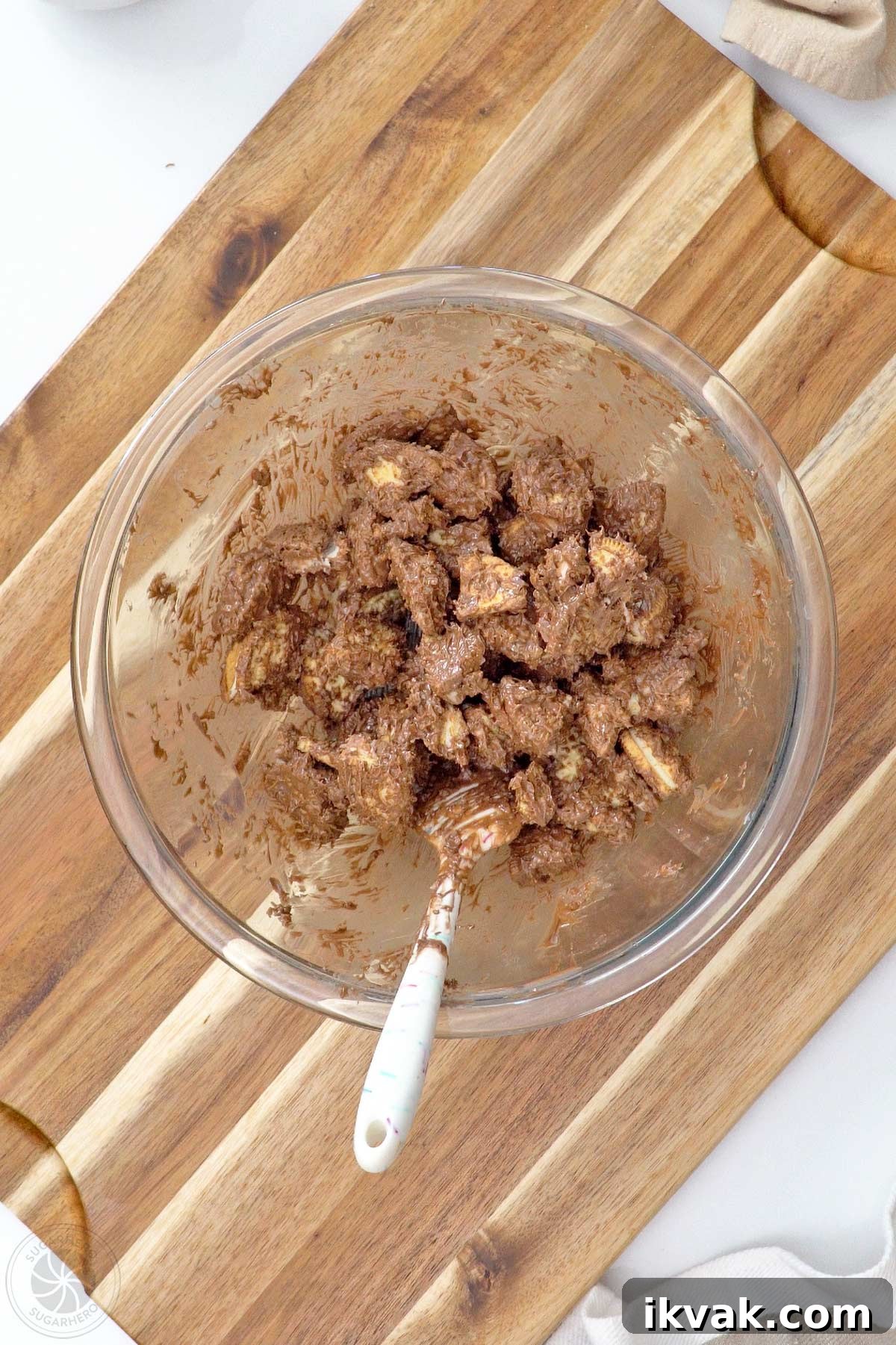 Mixture of melted coating, popping candy, and chopped cookie pieces in a large glass bowl.