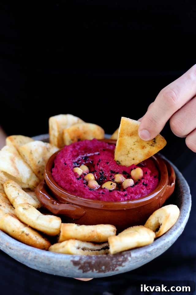 Hand Dipping a Pita Chip into Hummus