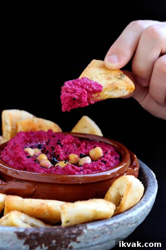 Holding a Pita Chip Dipped in Pink Hummus