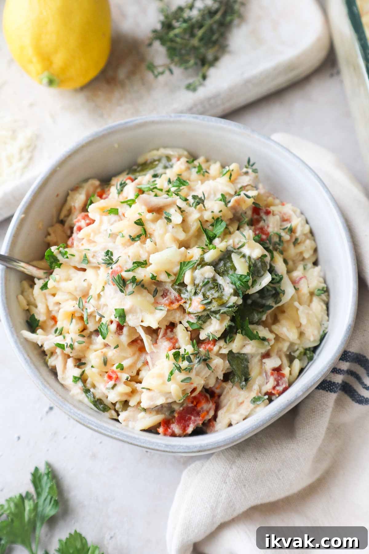 glass bowl with baked chicken orzo pasta topped with parsley.