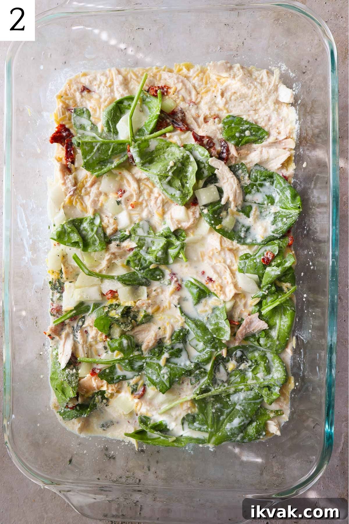 glass baking dish with creamy orzo with spinach, chicken, and sundried tomatoes.