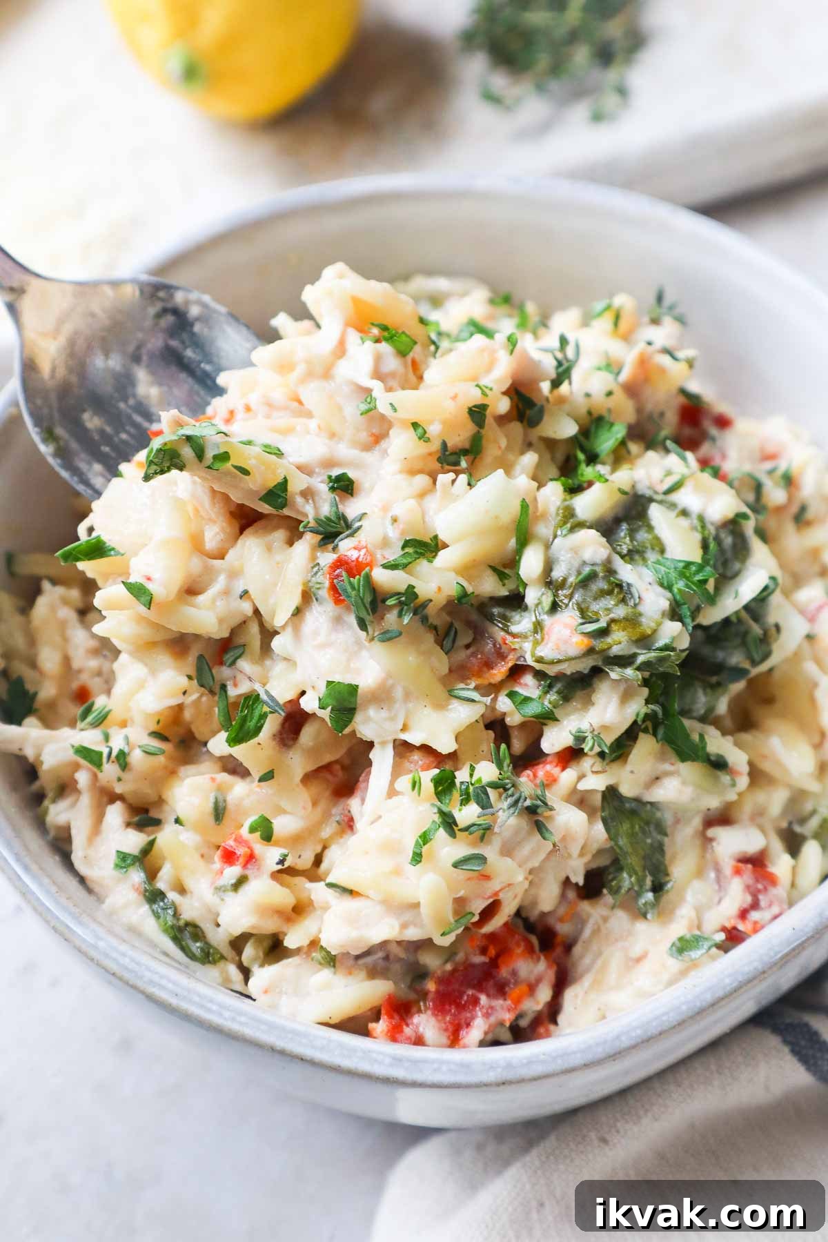 glass bowl with baked chicken orzo pasta topped with parsley.