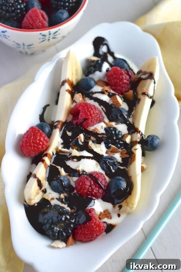 close-up of healthy banana split with Greek Yogurt, fresh berries and sugar-free homemade chocolate sauce 