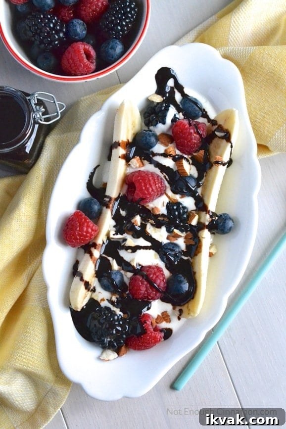 Healthy Banana Split filled with Greek Yogurt, berries and homemade clean eating chocolate sauce on an oval plate