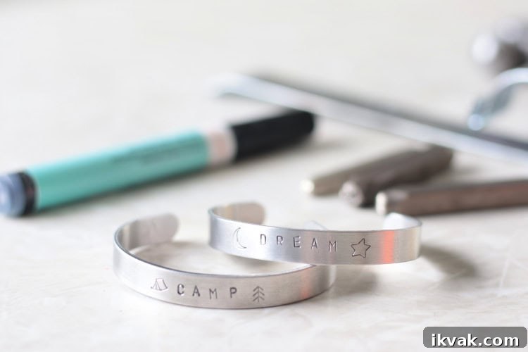 two metal stamped bracelts on table with marker and metal stamps