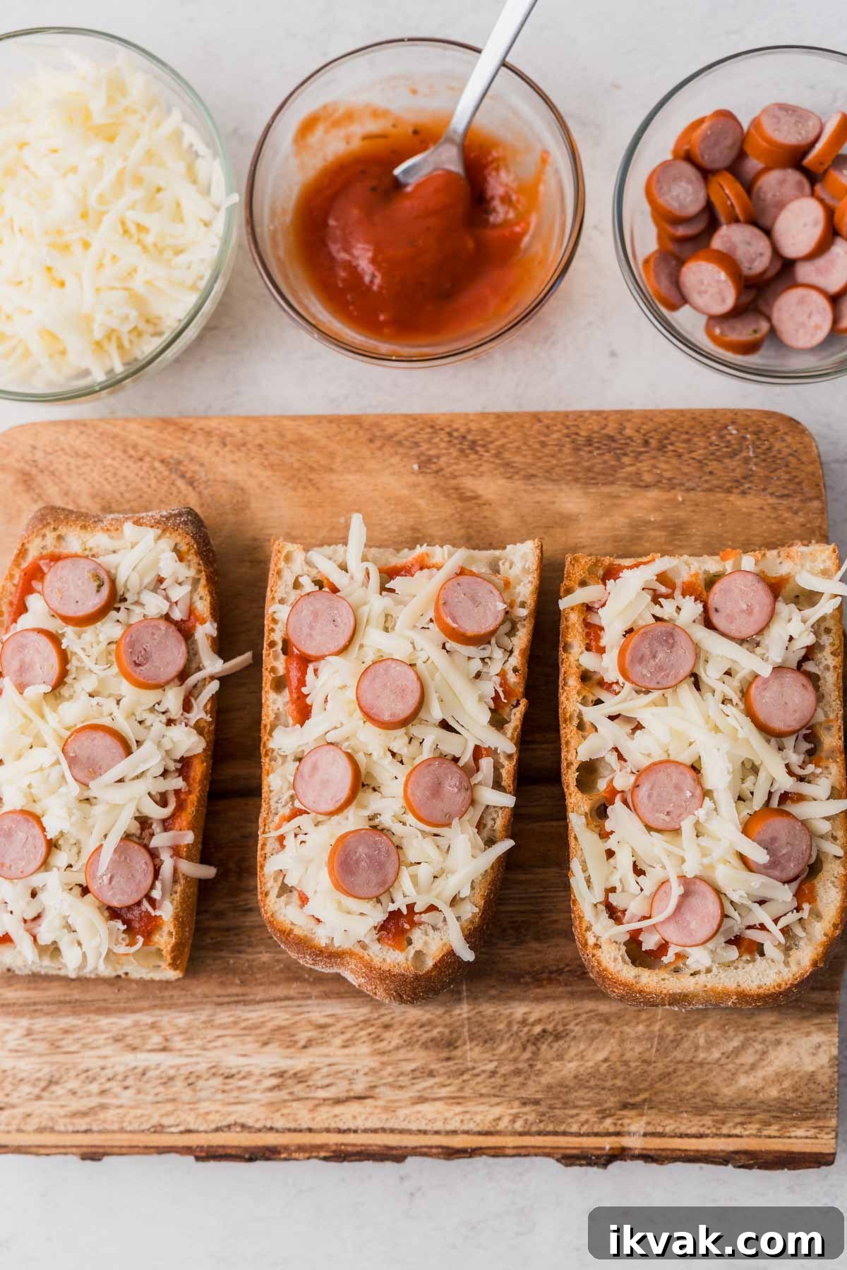 adding pizza sauce and toppings to the french bread.